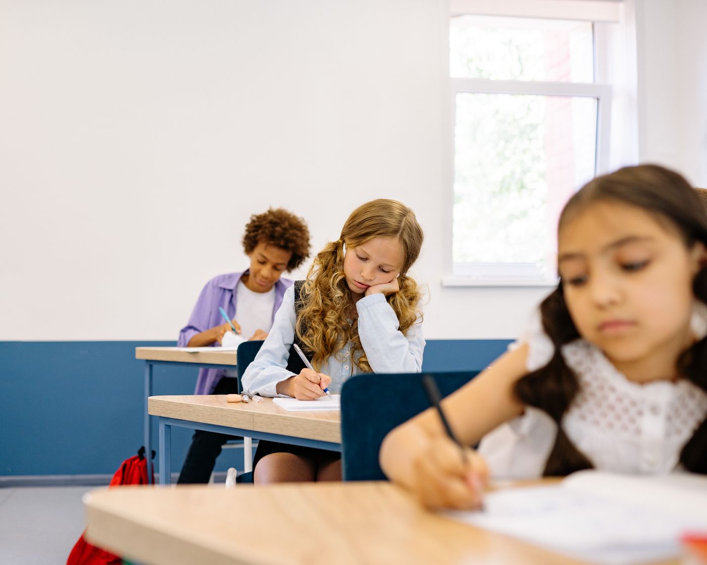 Students concentrating on their writing at classroom desks