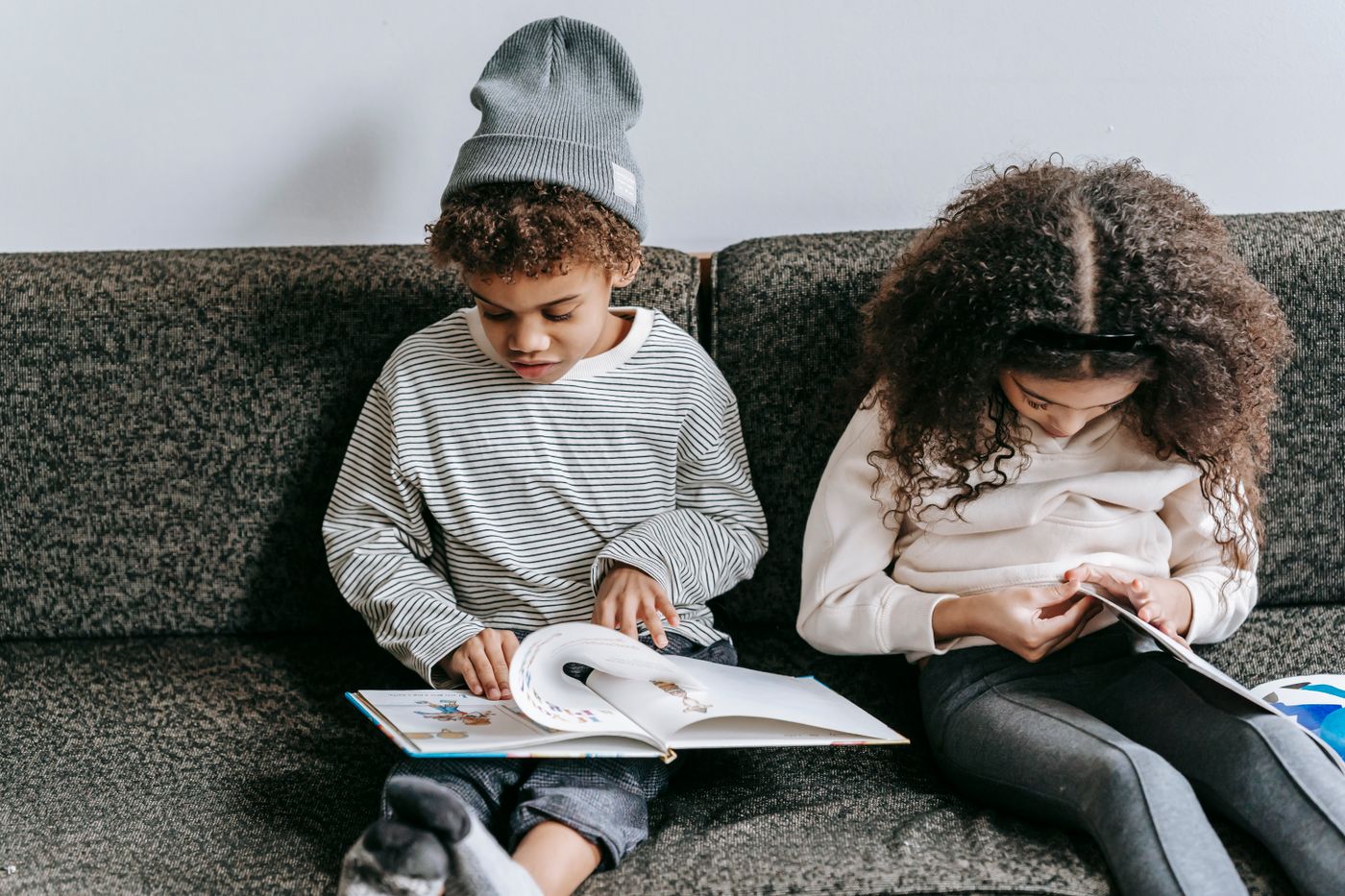Two Black children reading a colorful book together